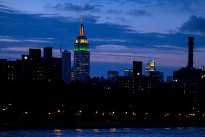 Illuminated buildings in city against cloudy sky