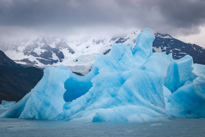 View of iceberg on sea against sky
