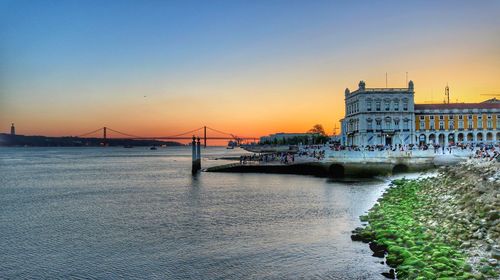Bridge over river in city at sunset