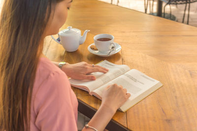 Midsection of woman using mobile phone while sitting on table