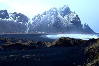 Scenic view of sea by snowcapped mountain against sky