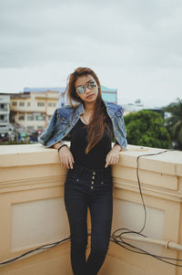 Portrait of young woman wearing sunglasses against sky