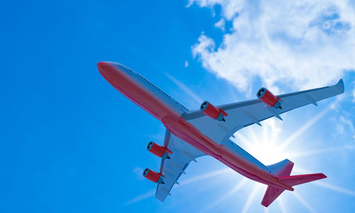 Passenger plane white red stripes flying in the sky on a bright blue day, white clouds.