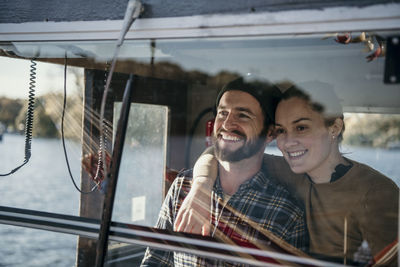 Smiling woman standing with arm around boyfriend in boat