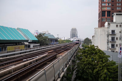 Railroad tracks amidst buildings in city against sky