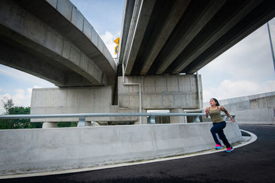 Full length of woman standing on bridge against sky in city