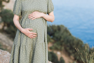 Pregnant woman wearing dress posing outdoors over nature background closeup. motherhood. maternity. 