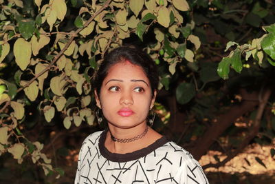 Beautiful young woman looking away against plants