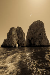 Rock formations in sea against clear sky