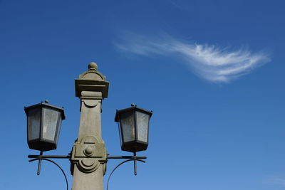 Low angle view of lamp posts against blue sky