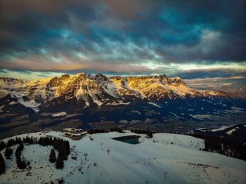 Snow covered landscape against sky during sunset