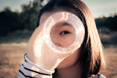 Close-up portrait of girl looking through bottle