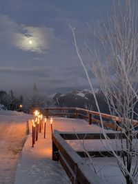 Scenic view of snow covered illuminated park against sky at dusk