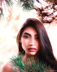 Portrait of young woman by plant