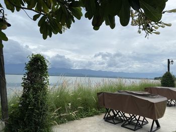 Chairs and table by swimming pool against sky