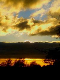 Silhouette trees on landscape against sunset sky