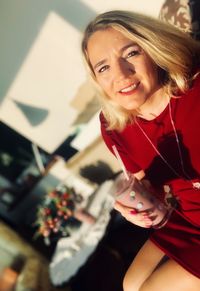 Portrait of beautiful woman holding drink while sitting in cafe