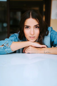 Portrait of beautiful young woman sitting on table