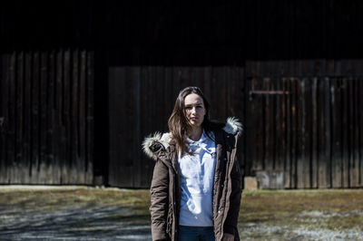 Portrait of beautiful young woman standing against wall