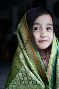 Portrait of cute asian toddler, kid, girl wearing traditional songket shawl.