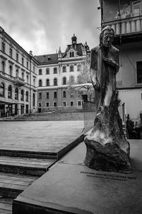 Statue by fountain in city against sky