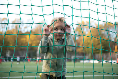 A boy croaks through a soccer net