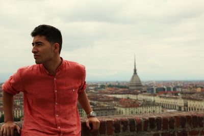 Man standing by cityscape against sky