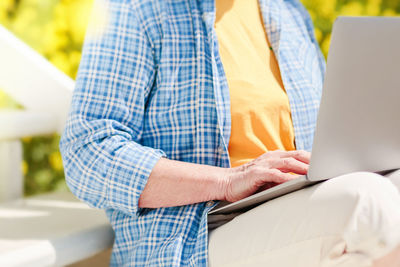Unrecognizable senior woman using laptop for distance learning outdoors
