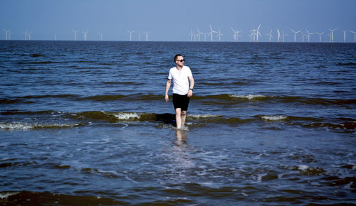 Full length of man standing on sea shore against sky