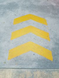 High angle view of yellow arrow symbol on road