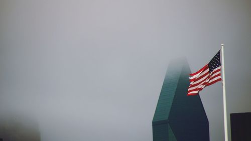 Low angle view of flag against buildings against clear sky