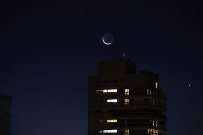 Low angle view of illuminated buildings against sky at night