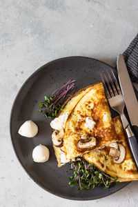 Classic egg omelette or omelet served with mushrooms, mozzarella and microgreens. breakfast. 