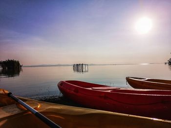 Boats moored in sea against sky during sunset