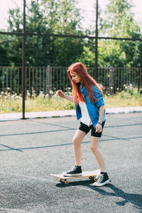 Cute teen girl rides a skateboard on a sports field