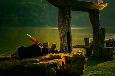 Person sitting on wood against trees