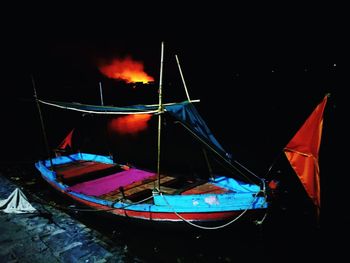 Boats moored on lake against sky at night