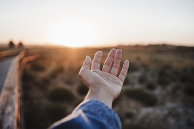 Woman showing palm of hand during sunset