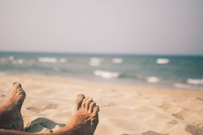Low section of man relaxing on beach