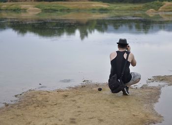 Full length of young man sitting on shore at lake