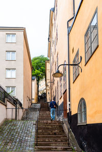 Rear view of man walking on staircase against building