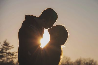 Silhouette couple kissing against sky during sunset