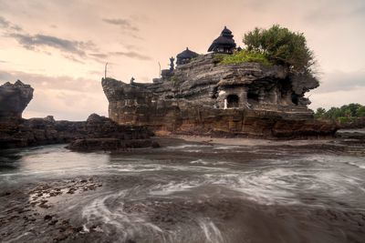 Rock formation at beach against sky