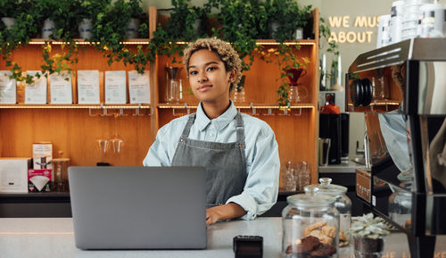 Portrait of young businesswoman using laptop while standing in office