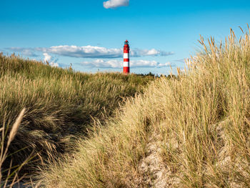 Lighthouse on beach by sea against sky