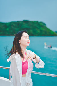 Young woman standing against sea