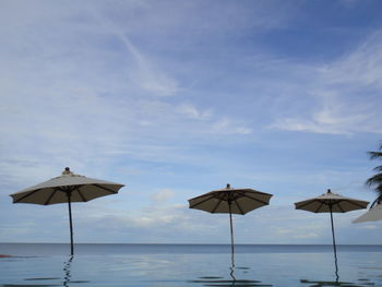 Umbrellas on beach against sky