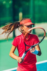 Girl practicing tennis while standing in court