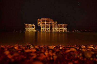 Reflection of illuminated water in sea against sky at night