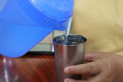 Close-up of hand pouring drink in glass